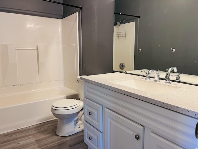 bathroom featuring toilet, vanity, wood finished floors, and shower / bathtub combination