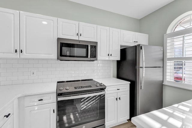 kitchen featuring white cabinets, appliances with stainless steel finishes, light countertops, and backsplash