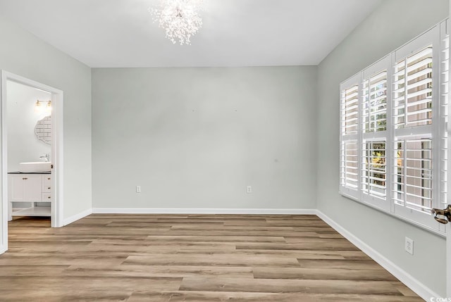 spare room featuring light hardwood / wood-style flooring and a notable chandelier