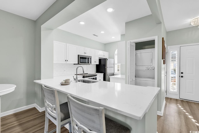 kitchen featuring stacked washer and dryer, appliances with stainless steel finishes, dark wood-style flooring, and tasteful backsplash