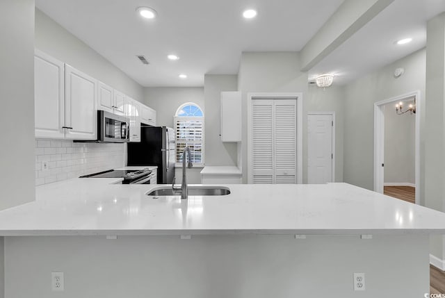 kitchen with white cabinets, sink, kitchen peninsula, appliances with stainless steel finishes, and dark hardwood / wood-style floors