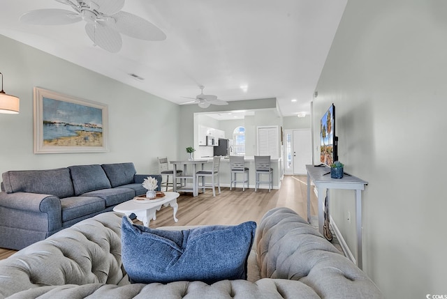 living area with light wood-style flooring, visible vents, and a ceiling fan