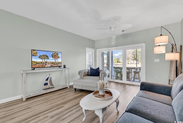 living room with a ceiling fan, baseboards, and wood finished floors