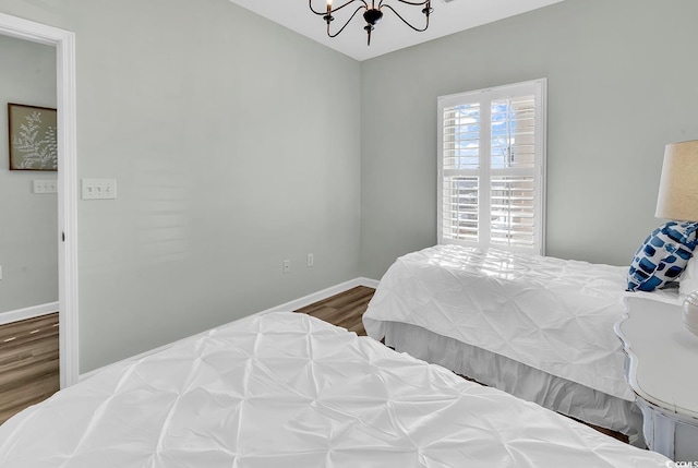 bedroom featuring baseboards, a chandelier, and wood finished floors