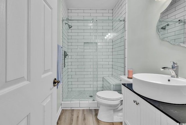 full bathroom with vanity, a shower stall, toilet, and wood finished floors