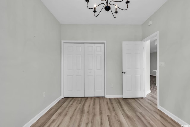 unfurnished bedroom featuring a notable chandelier, a closet, and light hardwood / wood-style flooring