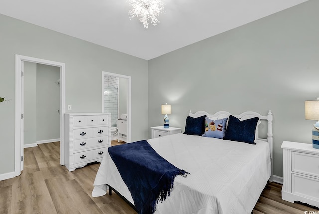 bedroom with a chandelier, ensuite bathroom, wood finished floors, and baseboards