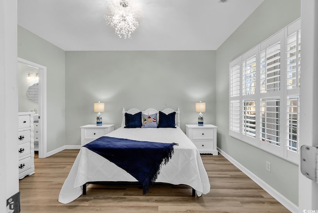 bedroom featuring light wood-type flooring, baseboards, and a chandelier