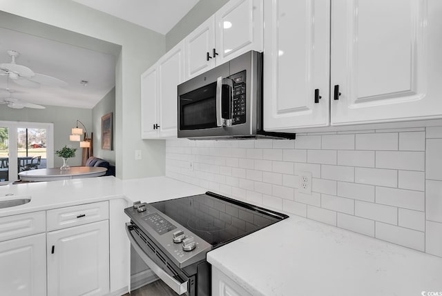 kitchen featuring white cabinets, stainless steel microwave, light countertops, and electric stove