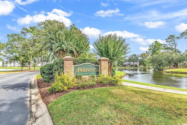 community / neighborhood sign with a water view and a lawn