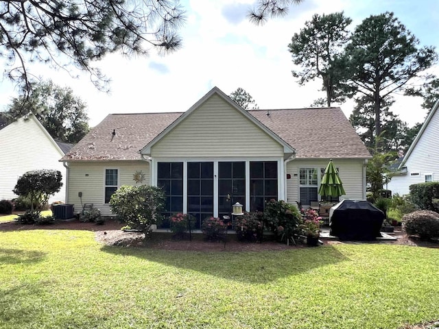 back of house with a sunroom, a lawn, and central AC