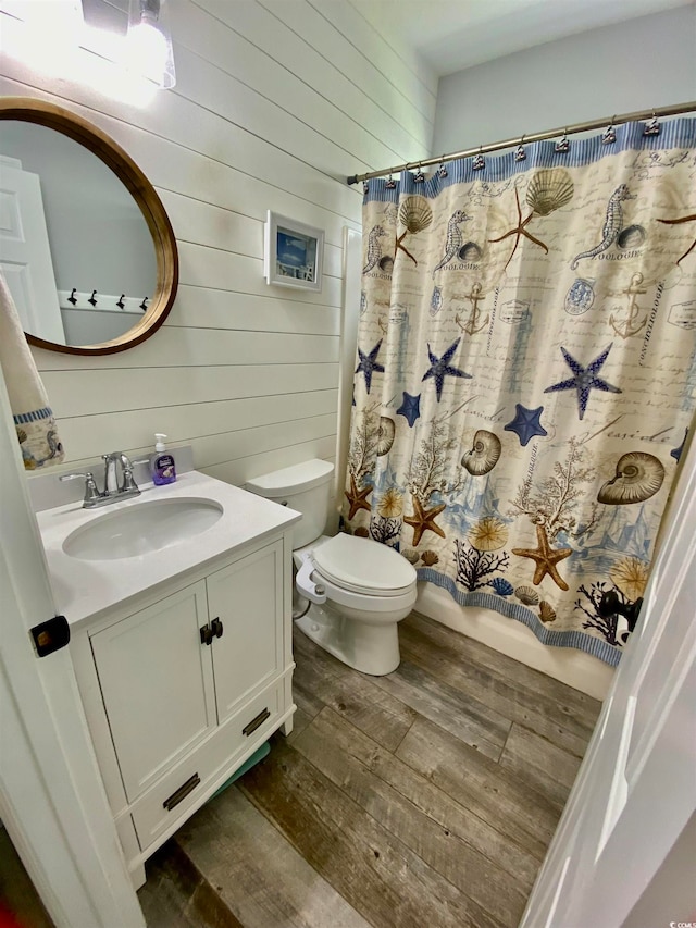 bathroom with vanity, wood walls, toilet, and hardwood / wood-style flooring