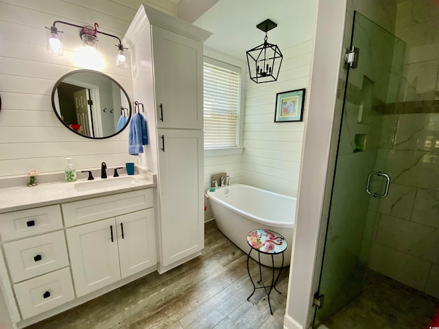 bathroom featuring wood walls, vanity, hardwood / wood-style floors, and plus walk in shower