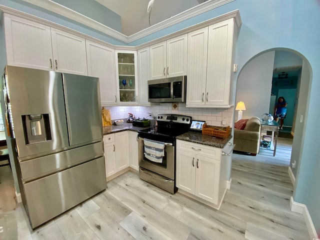 kitchen with dark stone countertops, light hardwood / wood-style flooring, stainless steel appliances, and white cabinets