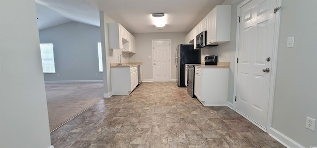 kitchen featuring white cabinetry, vaulted ceiling, appliances with stainless steel finishes, and light colored carpet