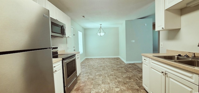 kitchen with appliances with stainless steel finishes, decorative light fixtures, and sink