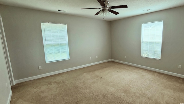 carpeted empty room featuring ceiling fan, a healthy amount of sunlight, and a textured ceiling