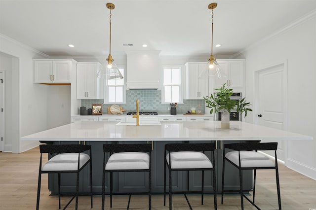 kitchen with a spacious island, white cabinets, crown molding, and custom range hood