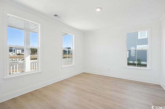 empty room featuring visible vents, baseboards, crown molding, and light wood-style floors