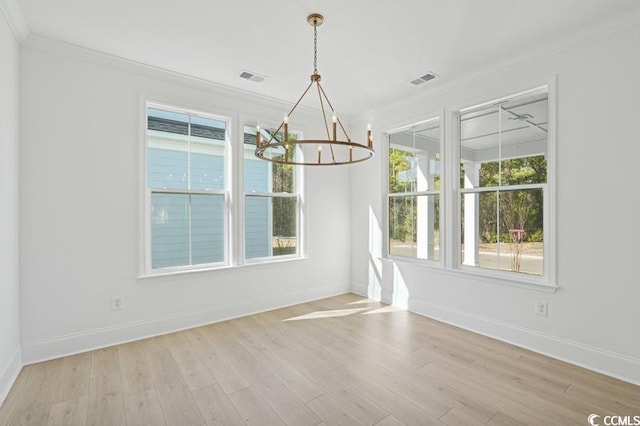 unfurnished dining area with an inviting chandelier, crown molding, light wood-type flooring, and baseboards