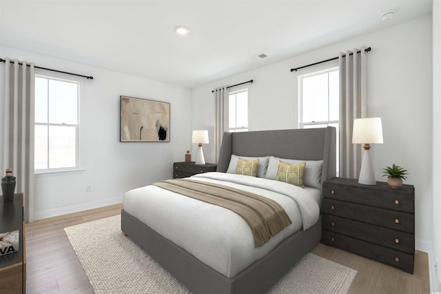 bedroom with visible vents, baseboards, and light wood finished floors