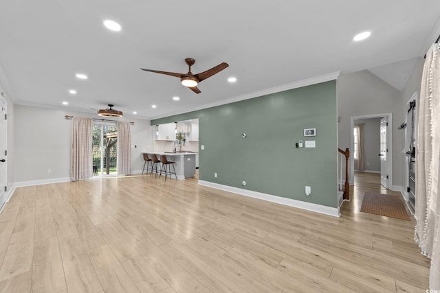 unfurnished living room featuring ceiling fan, lofted ceiling, ornamental molding, and light wood-type flooring