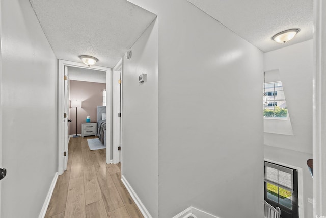 hall featuring light hardwood / wood-style floors and a textured ceiling