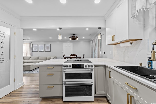 kitchen with decorative light fixtures, range with two ovens, and crown molding