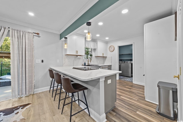 kitchen with white cabinetry, washing machine and clothes dryer, backsplash, hanging light fixtures, and kitchen peninsula