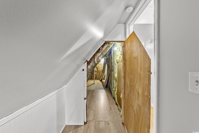 corridor featuring light wood-type flooring and lofted ceiling