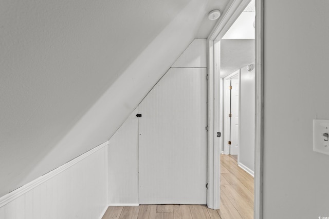 hallway featuring vaulted ceiling and light hardwood / wood-style floors