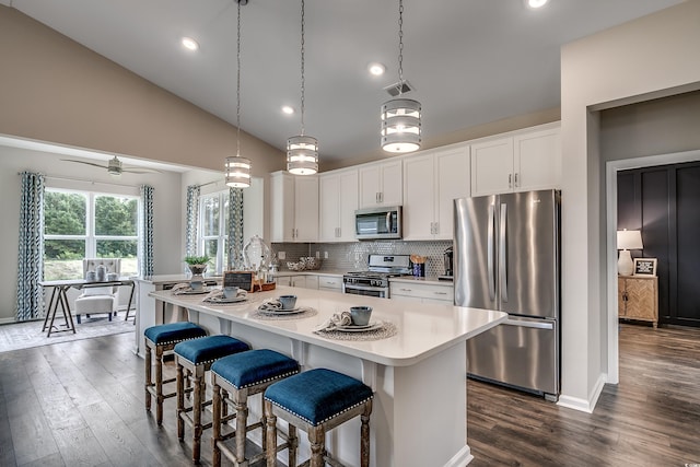 kitchen featuring appliances with stainless steel finishes, white cabinetry, vaulted ceiling, and dark hardwood / wood-style floors