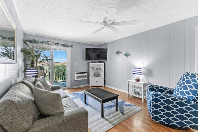 living room with a textured ceiling, wooden walls, hardwood / wood-style floors, and ceiling fan