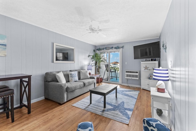 living room with heating unit, wood walls, a textured ceiling, ceiling fan, and light hardwood / wood-style flooring