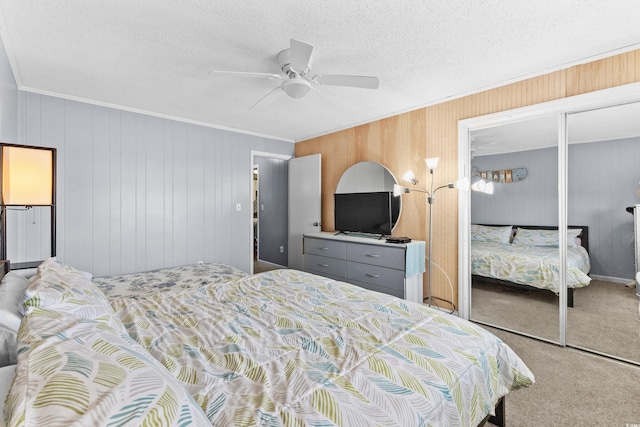 carpeted bedroom with ceiling fan, a textured ceiling, a closet, and wood walls