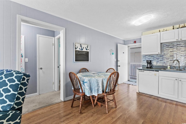 dining room featuring wooden walls, crown molding, hardwood / wood-style floors, and sink