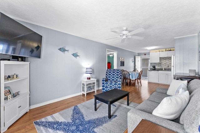 1919 Spring St Unit B-31, North Myrtle Beach, SC 29582 - living area featuring light wood-type flooring, ceiling fan, a textured ceiling, baseboards, and ornamental molding