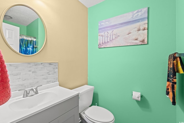 bathroom with a textured ceiling, vanity, and toilet