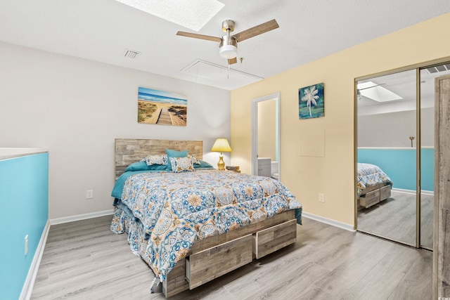 bedroom with a closet, ceiling fan, a skylight, and light wood-type flooring