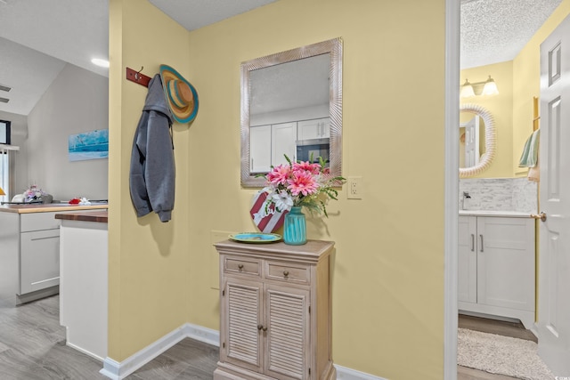 hallway with baseboards, wood finished floors, and a textured ceiling