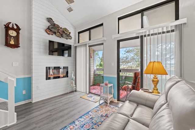 living room featuring wood-type flooring, high vaulted ceiling, and a large fireplace