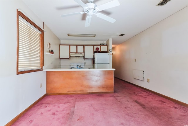 kitchen featuring kitchen peninsula, white appliances, ceiling fan, and light colored carpet