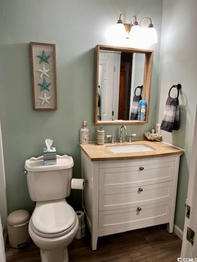 bathroom with wood-type flooring, vanity, and toilet