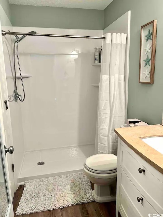 bathroom with a shower with curtain, vanity, hardwood / wood-style floors, and toilet