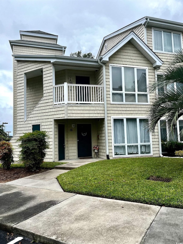 view of front facade with a balcony and a front lawn