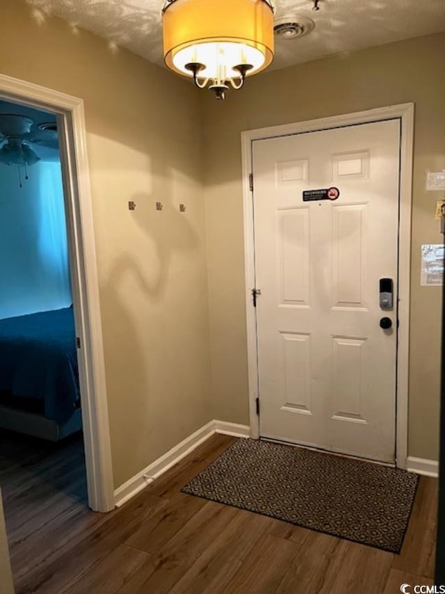 doorway with a textured ceiling and dark hardwood / wood-style flooring