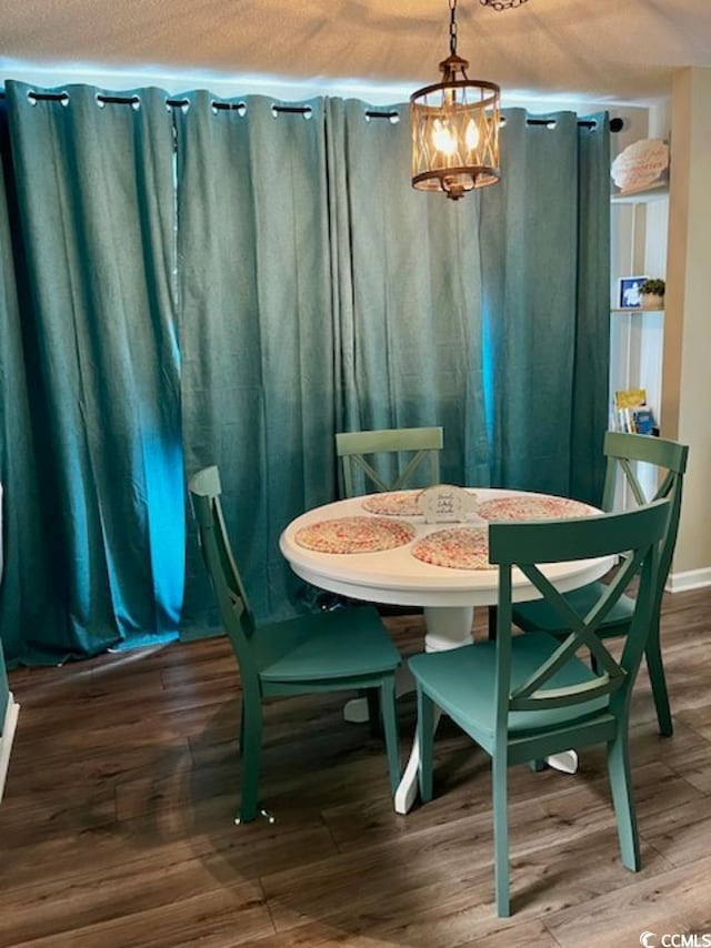 dining room with a textured ceiling, dark wood-type flooring, and a notable chandelier