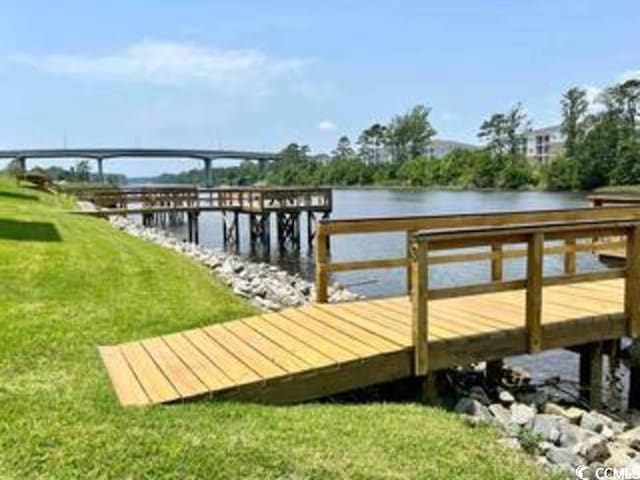 view of dock with a lawn and a water view