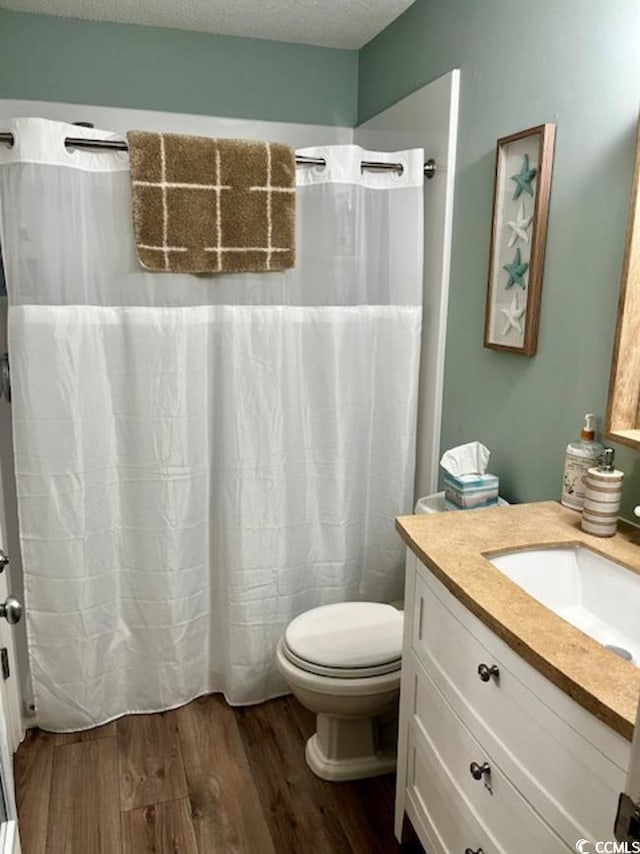 bathroom featuring vanity, toilet, a textured ceiling, hardwood / wood-style floors, and a shower with shower curtain