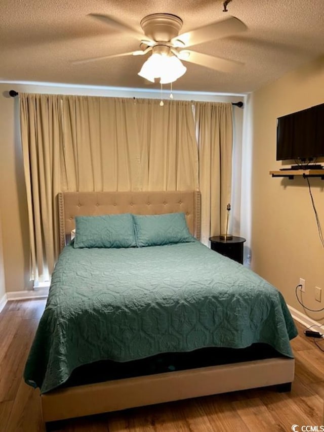 bedroom with wood-type flooring, ceiling fan, and a textured ceiling